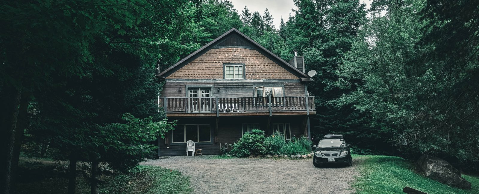 brown wooden house near green trees under white clouds during daytime