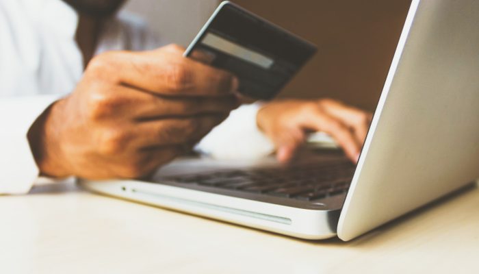 person using laptop computer holding card