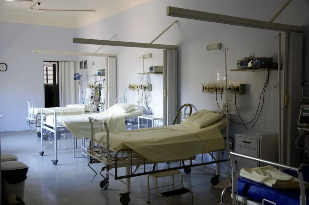 Spacious hospital room with several empty beds and medical equipment, emphasizing healthcare and hygiene